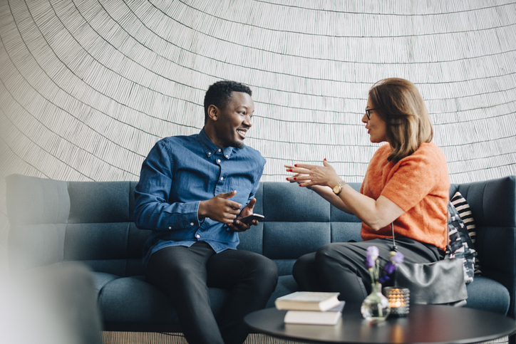 Two individuals sitting down in conversation to assess their professional chemistry