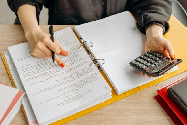 A person checking paperwork and making calculations